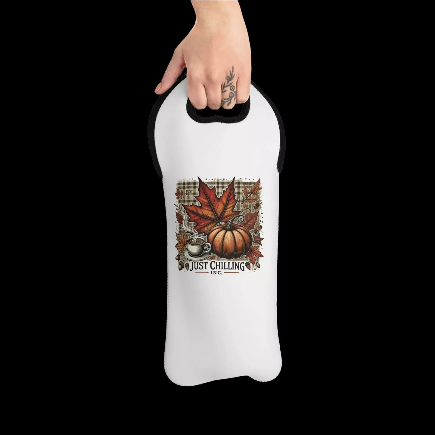 A person's hand holding a white wine carrier with a printed design of autumn leaves, a pumpkin, and a coffee cup.