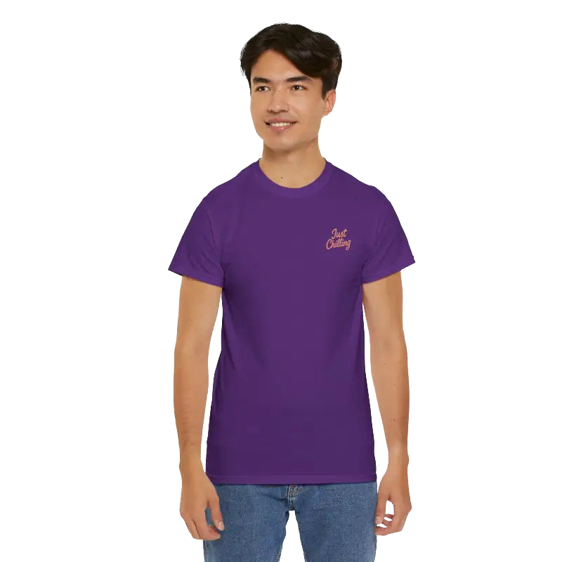 A young man wearing a purple t-shirt with a logo on it, smiling at the camera.