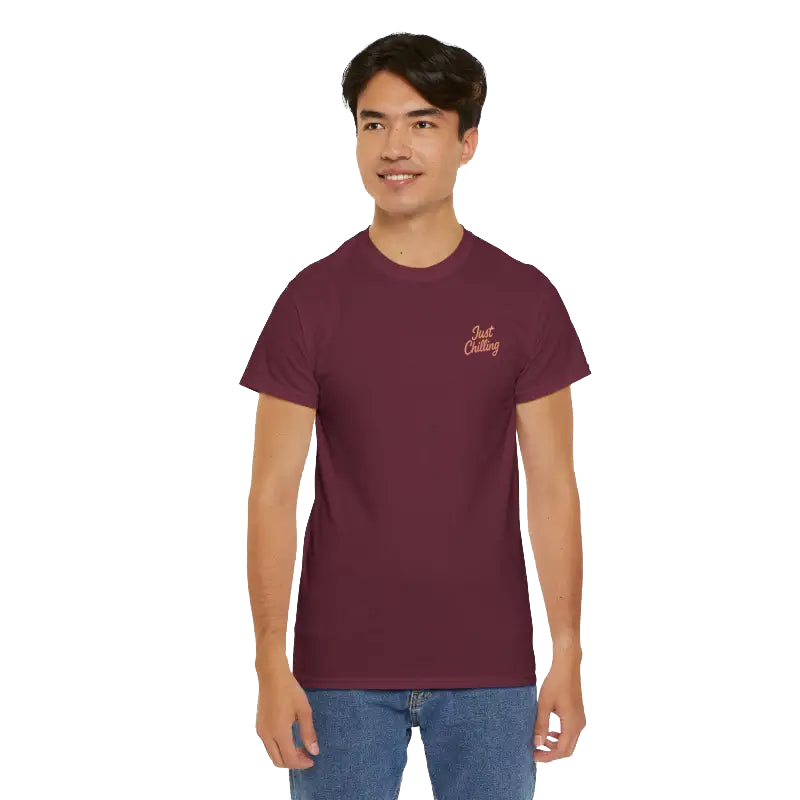 A young man wearing a maroon t-shirt with a logo on the left side of his chest, smiling at the camera.