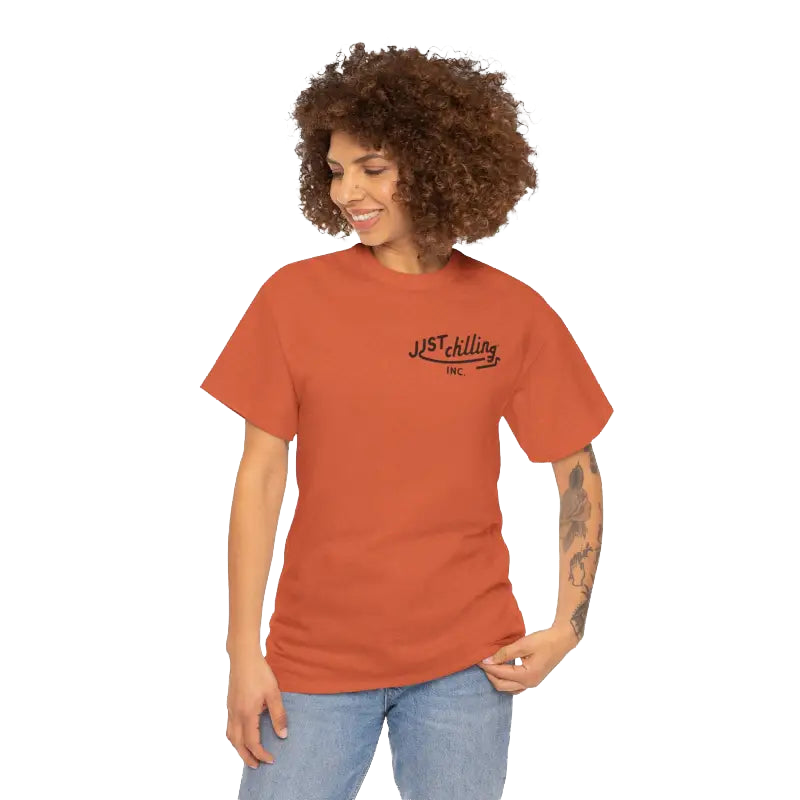 A smiling woman with curly hair wearing an orange t-shirt with text on it.