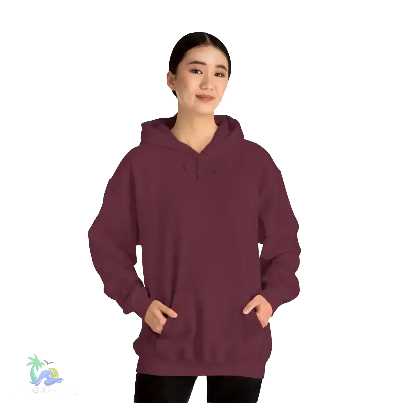 A woman wearing a maroon hoodie stands against a black background, looking directly at the camera with a neutral expression.