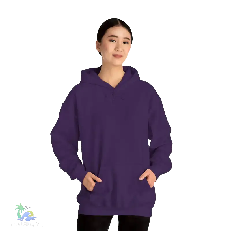 A woman wearing a purple hoodie stands against a black background, smiling at the camera.