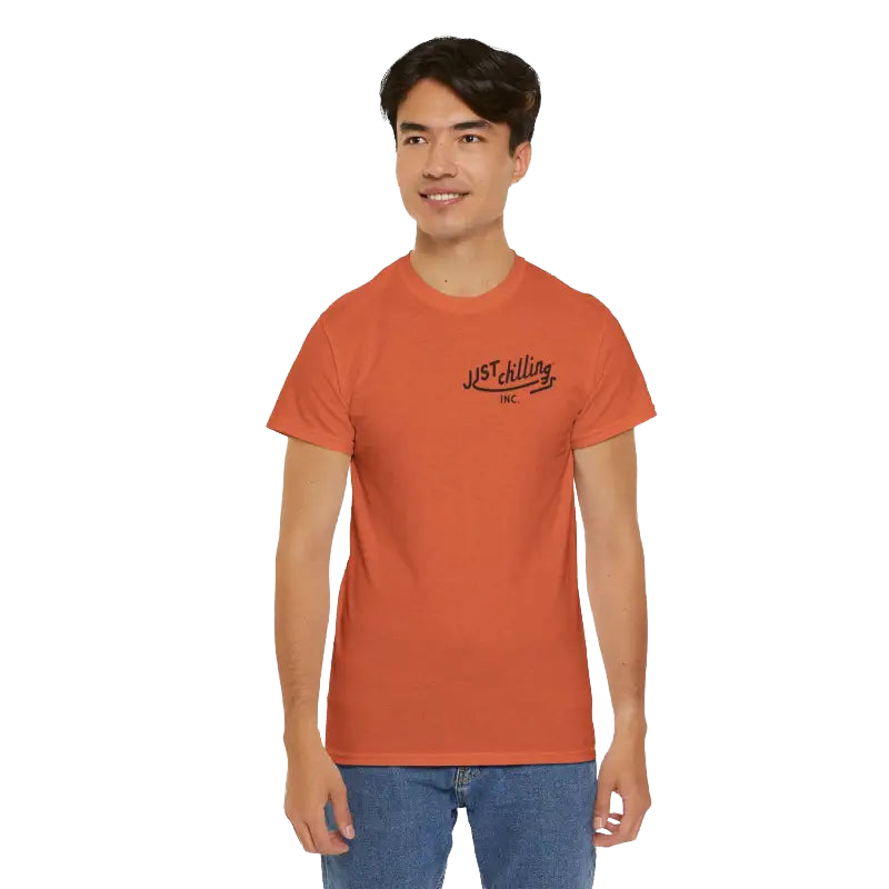 A young man wearing an orange t-shirt with a logo on it, smiling at the camera.