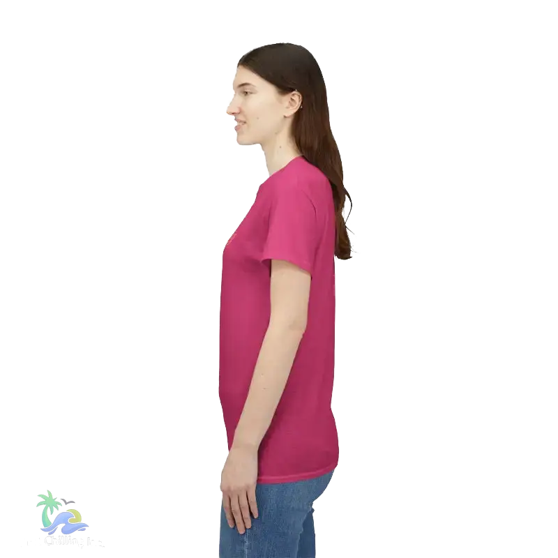 A woman wearing a pink t-shirt stands against a black background.