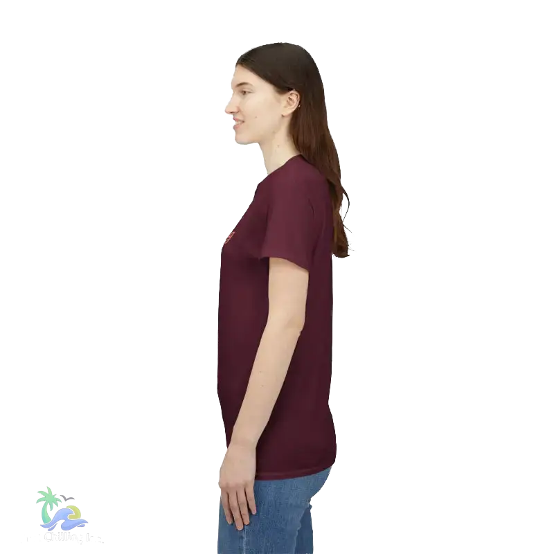 A woman wearing a maroon t-shirt stands against a black background.