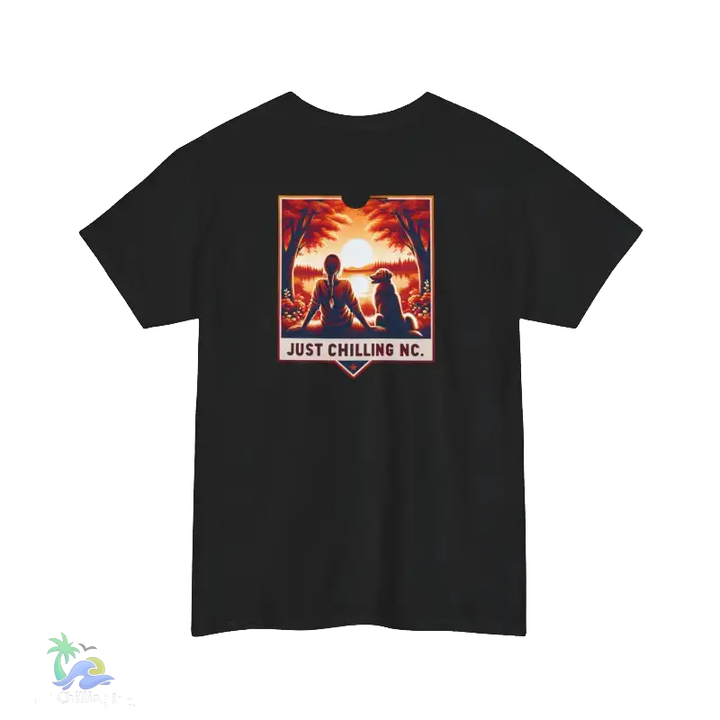A black t-shirt with a graphic design depicting a person sitting in a relaxed pose, with a sunset in the background. The text "JUST CHILLING NC" is displayed below the image.