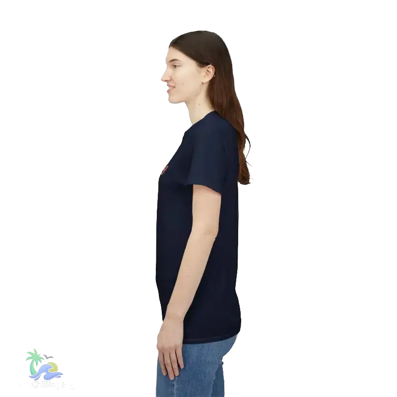 A woman with long brown hair is standing in profile, wearing a navy blue t-shirt and blue jeans.