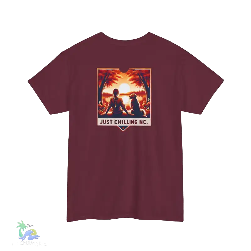A maroon t-shirt with a graphic design depicting a person sitting in a meditative pose with a dog, set against a sunset background. The text "JUST CHILLING NC" is displayed below the image.