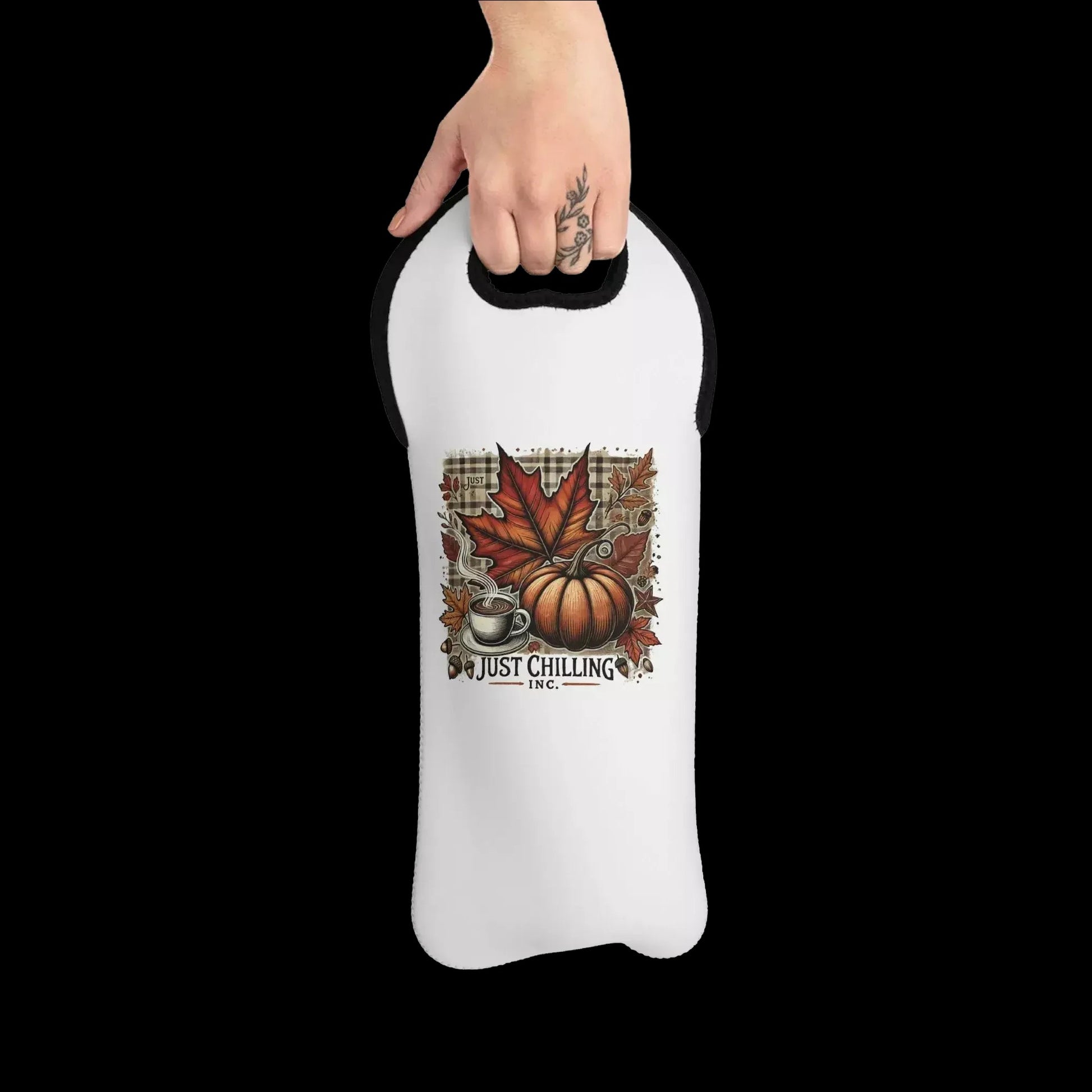 A person's hand holding a white wine carrier with a printed design of autumn leaves, a pumpkin, and a coffee cup.