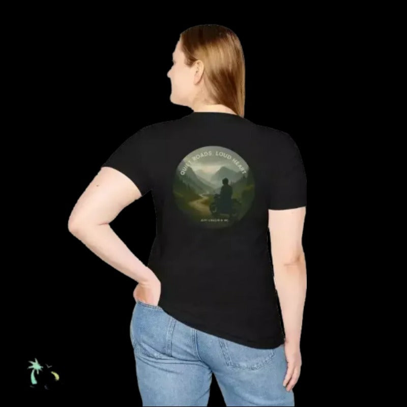 A woman wearing a black t-shirt with a circular graphic on the back, featuring a silhouette of a person in a contemplative pose against a mountain landscape.