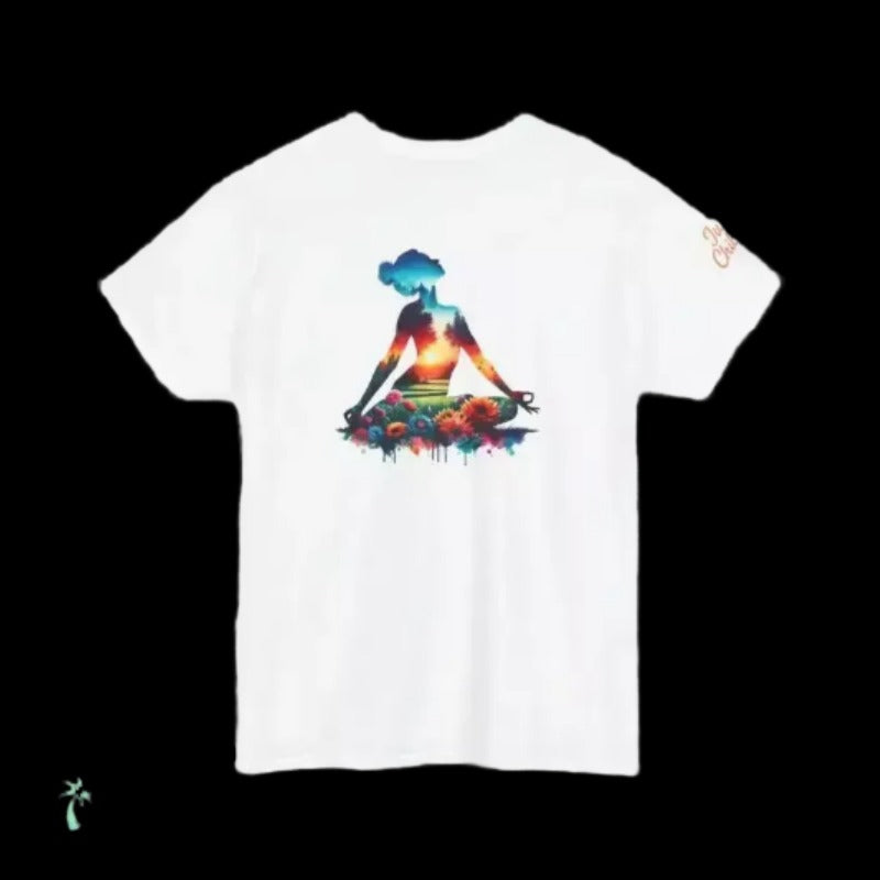 A white t-shirt with a colorful graphic design depicting a woman sitting in a meditative pose surrounded by a vibrant, abstract landscape.