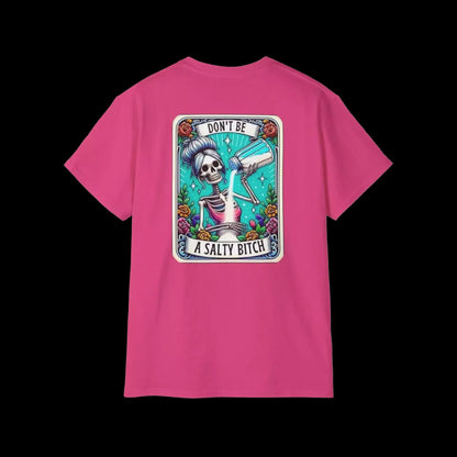 A pink t-shirt with a graphic design featuring a skeleton holding a bottle of alcohol and the text "DON'T BE A SALTY BITCH" against a colorful background.