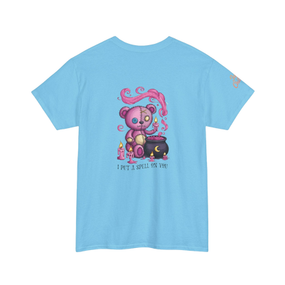 A light blue t-shirt with a colorful illustration of a teddy bear surrounded by candles and a cauldron, along with the text "I put a spell on you".