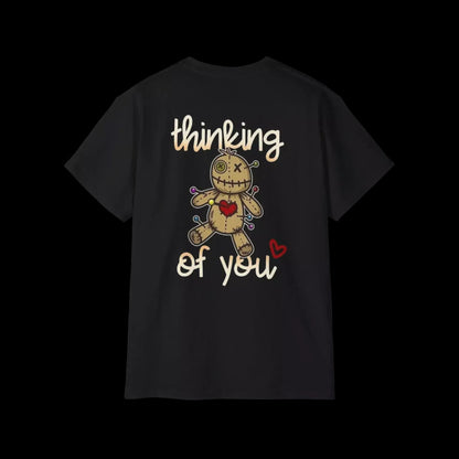 A black t-shirt with a graphic design featuring a voodoo doll with a heart and the text "Thinking of you" printed on it.