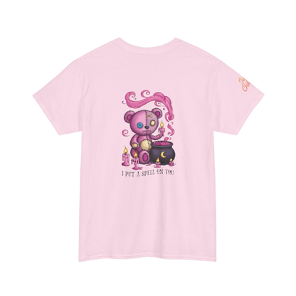 A pink t-shirt with a cartoon image of a teddy bear performing a spell on a cauldron, accompanied by the text "I put a spell on you".