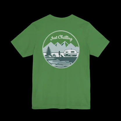 A green t-shirt with a circular graphic design featuring a mountain landscape, a camper van, and the text "Just Challenging".