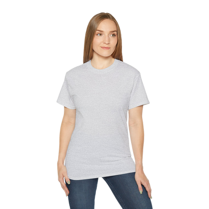 A woman with long brown hair wearing a gray t-shirt and blue jeans stands against a black background.