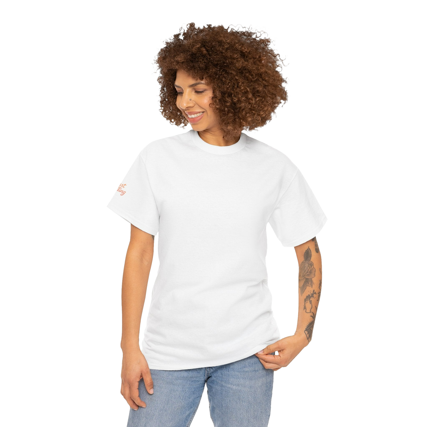 A smiling woman with curly hair wearing a white t-shirt and blue jeans stands against a black background.