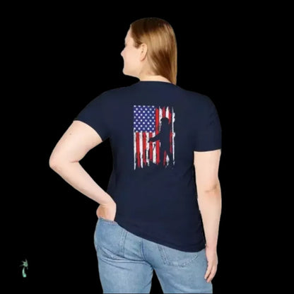 A woman wearing a navy blue t-shirt with an American flag design on the back, standing against a black background.