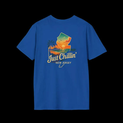A blue t-shirt with a graphic design depicting a sunset over a beach and palm trees, along with the text "Just Chillin' NEW JERSEY".