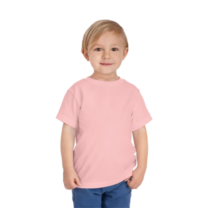 A young child wearing a pink t-shirt and blue pants stands against a black background, smiling at the camera.