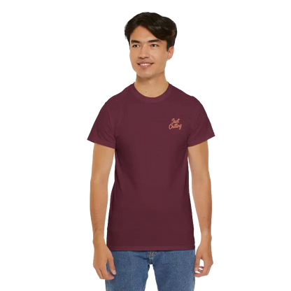 A young man wearing a maroon t-shirt with a logo on the left side of his chest, smiling at the camera.