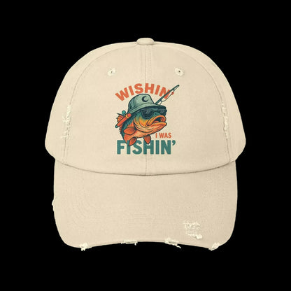 A beige baseball cap with a graphic design featuring a fish wearing a helmet and the text "Wishin' I was fishin'".