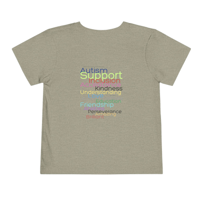 The image is a t-shirt with a graphic design featuring a list of positive traits or characteristics, such as Autism, Support, Inclusion, Kindness, Understanding, Education, Perserverance, and Friendship, all written in a colorful, stylized font.
