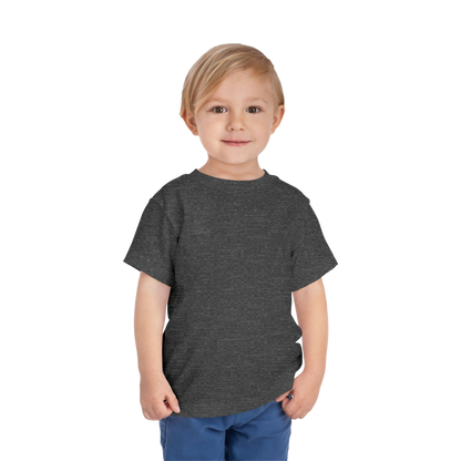 A young boy with blonde hair is standing against a black background, wearing a gray t-shirt and blue pants.