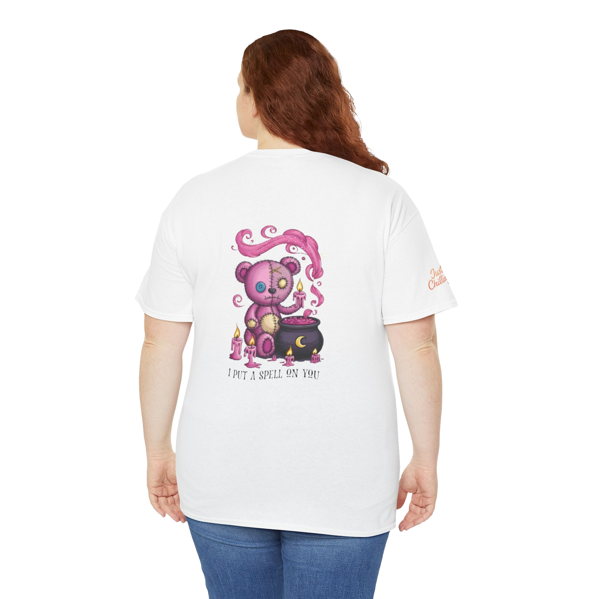 A woman wearing a white t-shirt with a colorful illustration of a teddy bear and a cauldron on it.