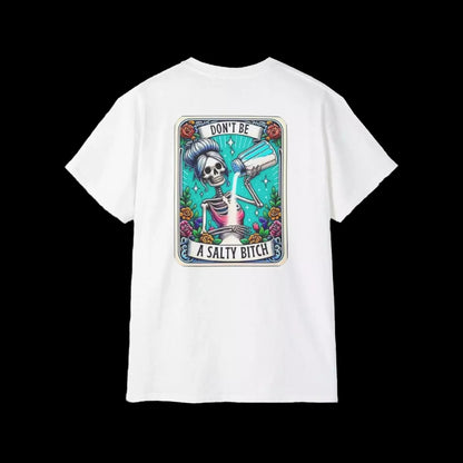 A white t-shirt with a graphic design featuring a skeleton wearing a sombrero and holding a bottle of alcohol, surrounded by colorful flowers and text that reads "DON'T BE A SALTY BITCH".