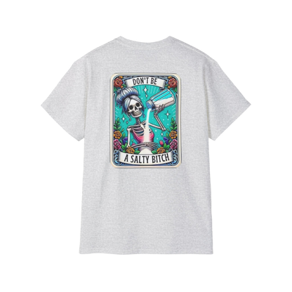 A white t-shirt with a graphic design featuring a skeleton wearing a sombrero and holding a bottle of alcohol, surrounded by colorful flowers and plants.