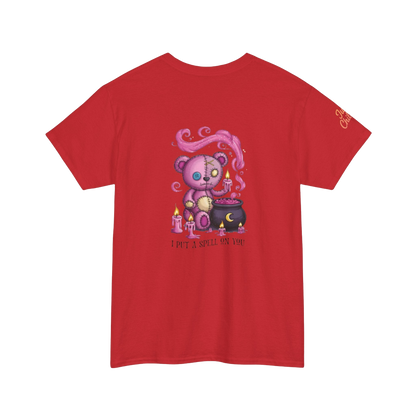A red t-shirt with a graphic design depicting a pink teddy bear surrounded by candles and a cauldron, with the text "I PUT SPELLING ON YOU" below the image.