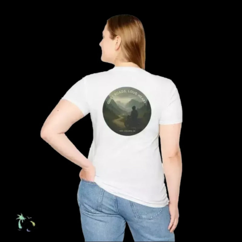A woman wearing a white t-shirt with a circular design on the back, featuring a silhouette of a person in a contemplative pose against a mountainous landscape.