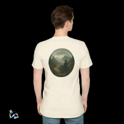 A person wearing a white t-shirt with a circular design on the back, depicting a person sitting in a meditative pose in front of a mountain landscape.