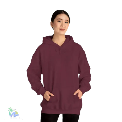 A woman wearing a maroon hoodie stands against a black background, looking directly at the camera with a neutral expression.