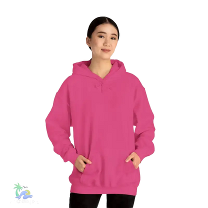 A woman wearing a bright pink hoodie stands against a black background.