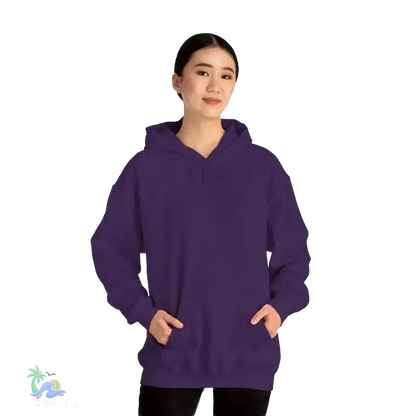 A woman wearing a purple hoodie stands against a black background, smiling at the camera.