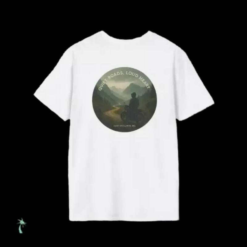 A white t-shirt with a circular graphic design featuring a person riding a motorcycle on a road through a mountainous landscape.