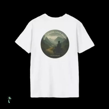 A white t-shirt with a circular graphic design featuring a person riding a motorcycle on a road through a mountainous landscape.