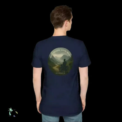 A person wearing a navy blue t-shirt with a graphic design on the back, depicting a person riding a motorcycle through a scenic landscape.