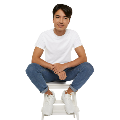 A young man wearing a white t-shirt and jeans is sitting on a white stool, smiling at the camera.