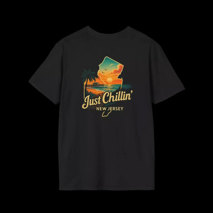 A black t-shirt with a graphic design depicting a sunset over a beach and palm trees, along with the text "Just Chillin' NEW JERSEY".