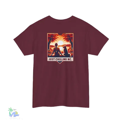 A maroon t-shirt with a graphic design depicting a person sitting in a meditative pose with a dog, set against a sunset background. The text "JUST CHILLING NC" is displayed below the image.