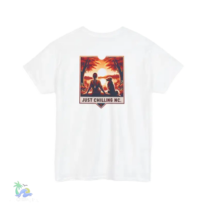 A white t-shirt with a graphic design depicting two people sitting in a relaxed pose, with a sunset in the background. The text "JUST CHILLING NC" is displayed below the image.