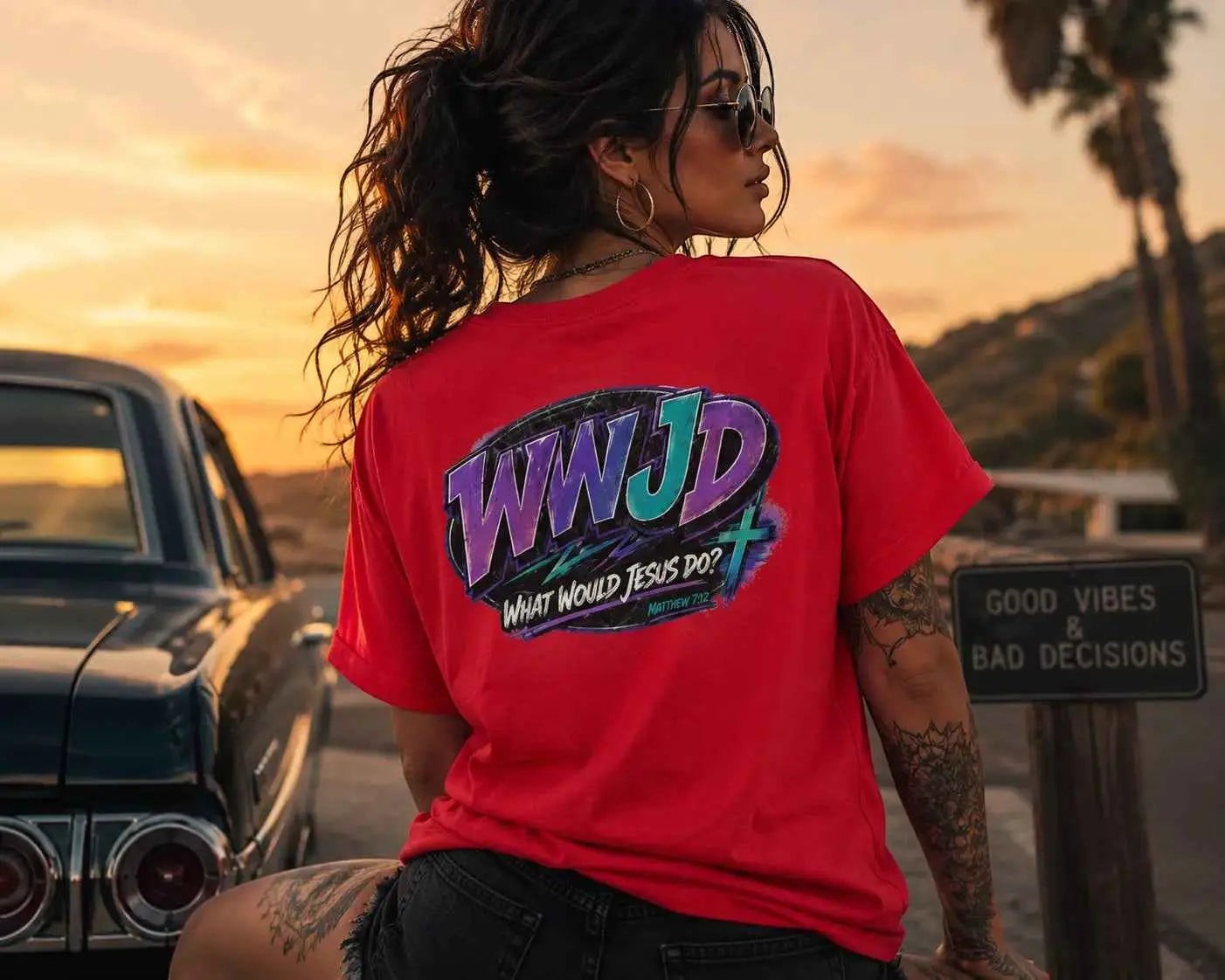 Just Chilling Shop red cotton t-shirt with a retro 90s WWJD graphic on the back, worn by a woman at sunset.